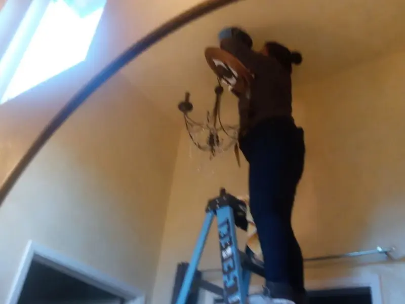Electrician installing a chandelier in a Gresham residence